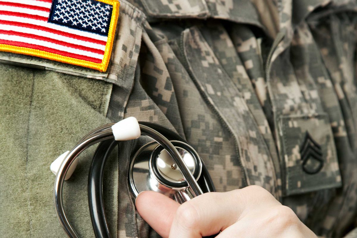 person in military uniform holding stethoscope to their chest